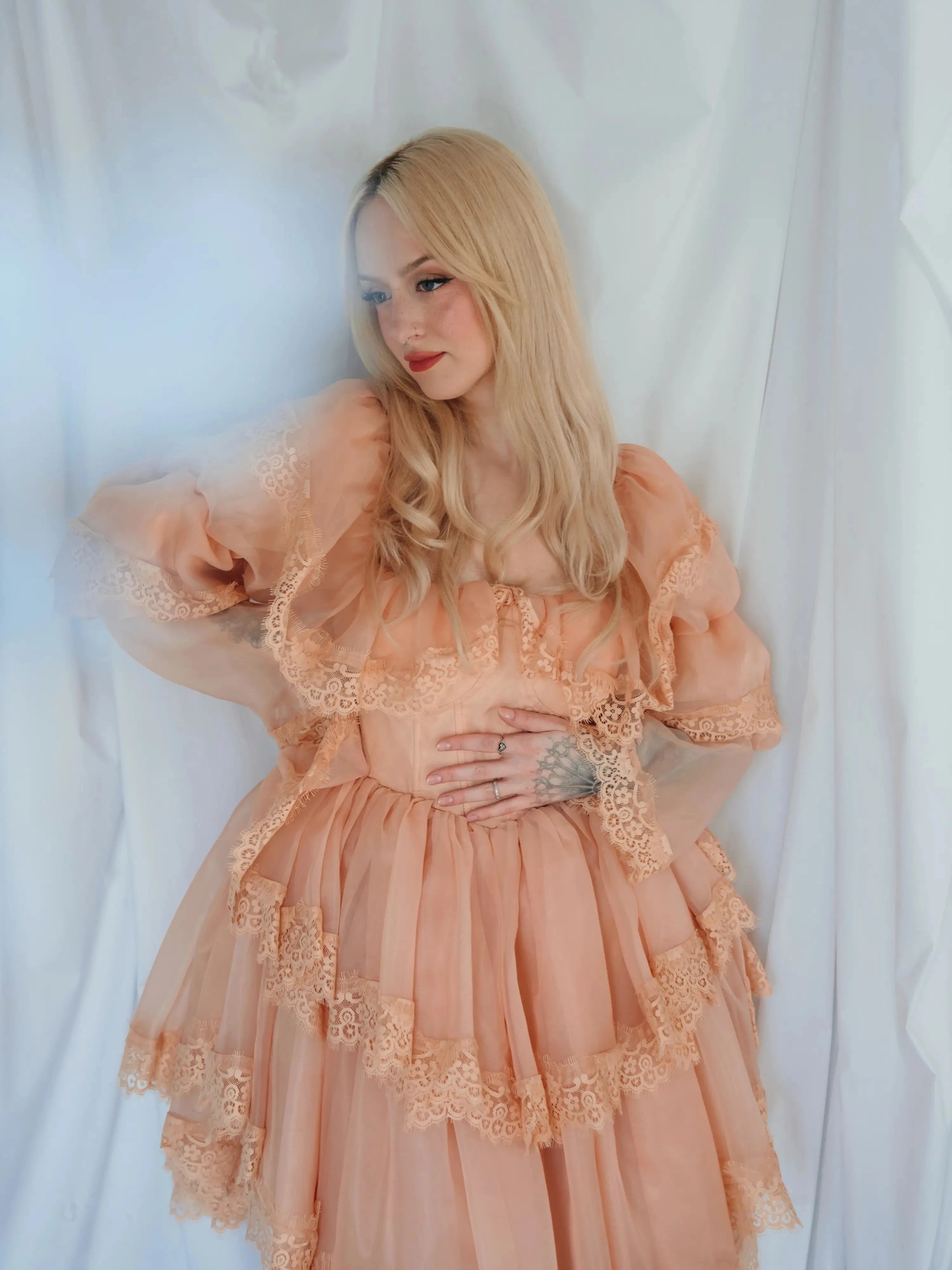 Model poses with hand on waist in the Midnight Symphony Mini Gown, emphasizing its whimsical silhouette and soft lace details.