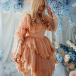 Smiling model in floral setting wearing the Midnight Symphony Mini Gown, a fairytale-inspired mini dress with layered lace and puff sleeves.