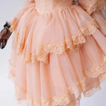 Close-up of the Midnight Symphony Mini Gown's tiered lace ruffles and structured bodice in pumpkin milk organza.