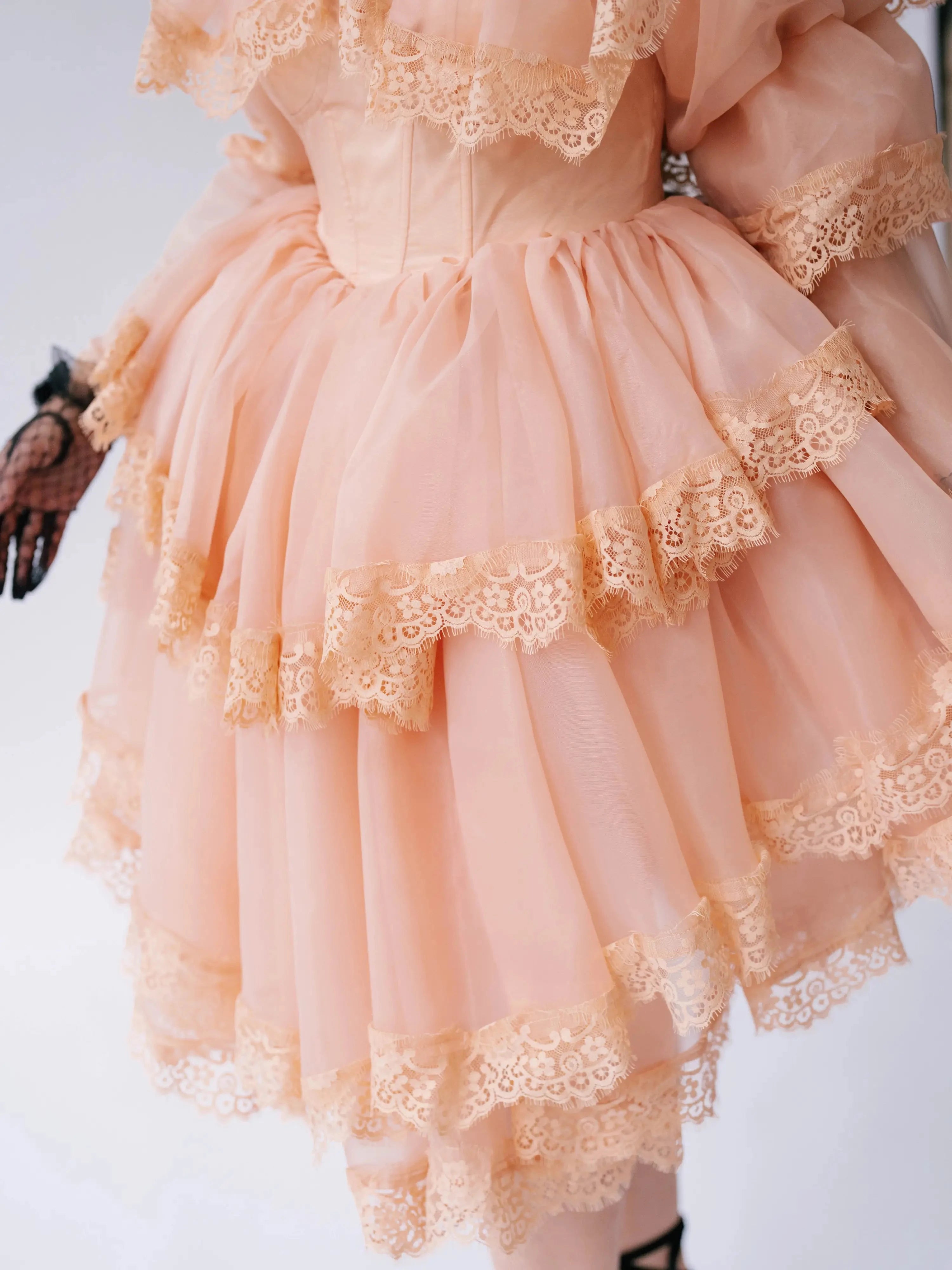 Close-up of the Midnight Symphony Mini Gown's tiered lace ruffles and structured bodice in pumpkin milk organza.