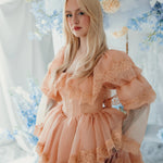 Model in floral backdrop wearing the Midnight Symphony Mini Gown, highlighting its vintage-inspired silhouette and lace detailing.