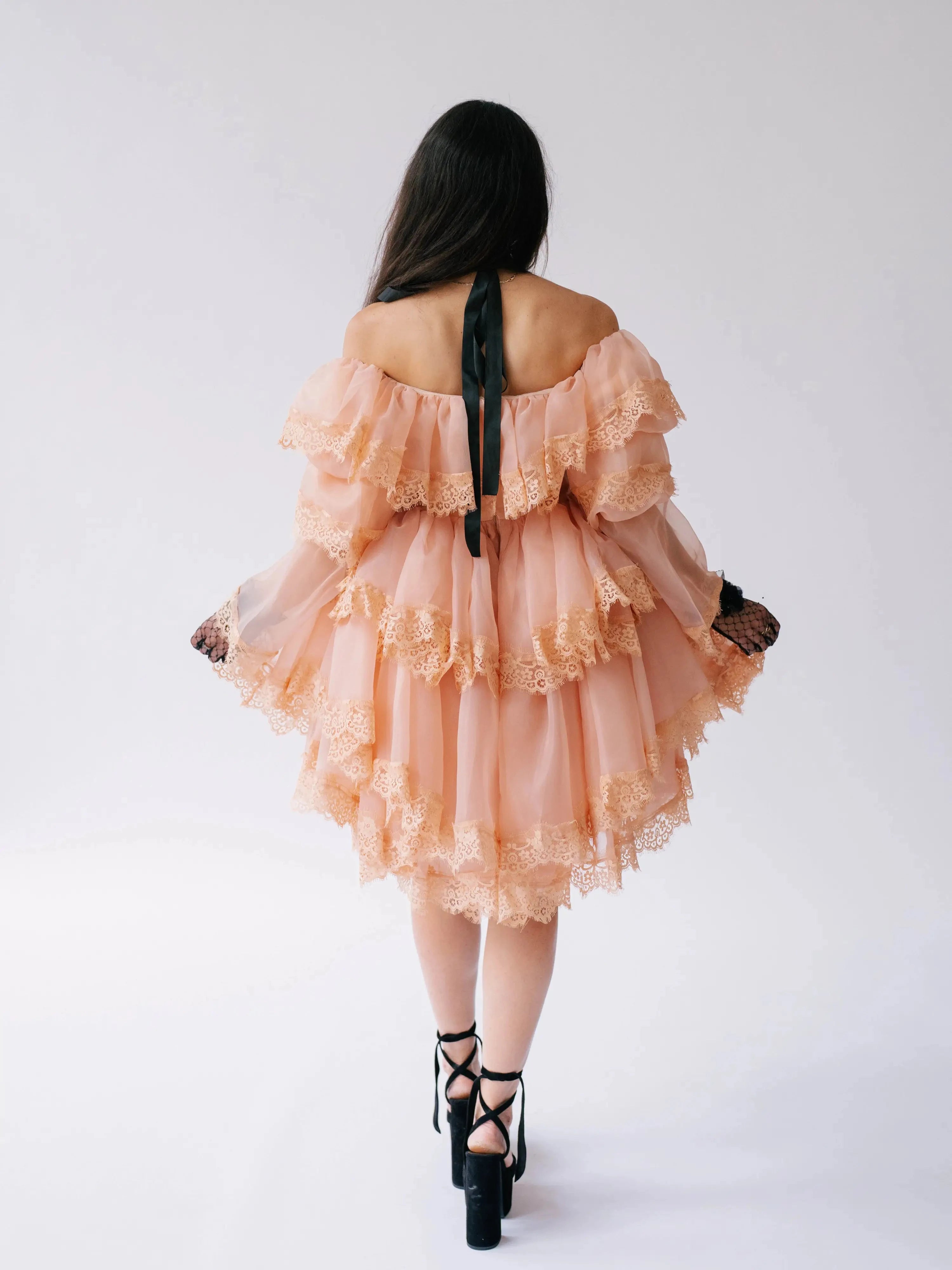 Back view of the Midnight Symphony Mini Gown showcasing tiered lace ruffles and a black ribbon halter tie in pumpkin milk organza.