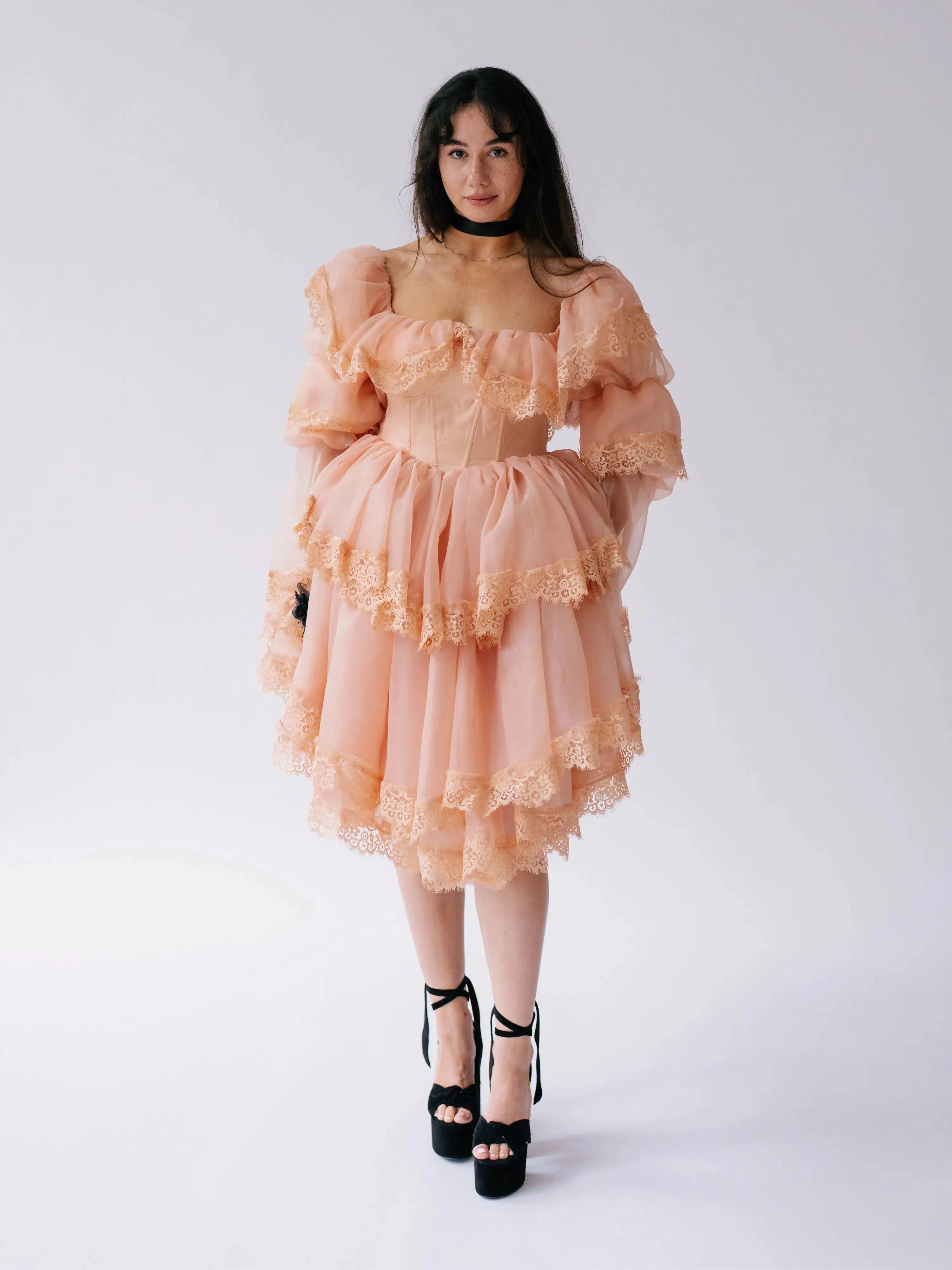 Front view of the Midnight Symphony Mini Gown in pumpkin milk organza with layered lace ruffles, styled with black platform heels.