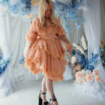 Model in floral setting wearing the Midnight Symphony Mini Gown, a whimsical pumpkin milk lace mini dress perfect for dreamy occasions.
