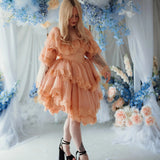 Model in floral setting wearing the Midnight Symphony Mini Gown, a whimsical pumpkin milk lace mini dress perfect for dreamy occasions.