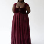 A floor-length scarlet red gown with a lace up corset bodice and flowing skirt.