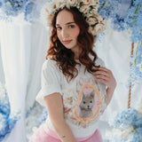 The Princess Kitten Tee styled with a floral crown and pink ruffled skirt, featuring whimsical cat artwork by Kaeti MacNeil.