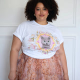 The Princess Kitten Tee styled casually with a floral skirt, highlighting the central kitten artwork and rolled sleeves for a relaxed fit.