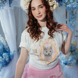 Model wearing The Princess Kitten Tee in a floral-themed setting, styled with a flower crown and pink ruffle skirt for a whimsical look.