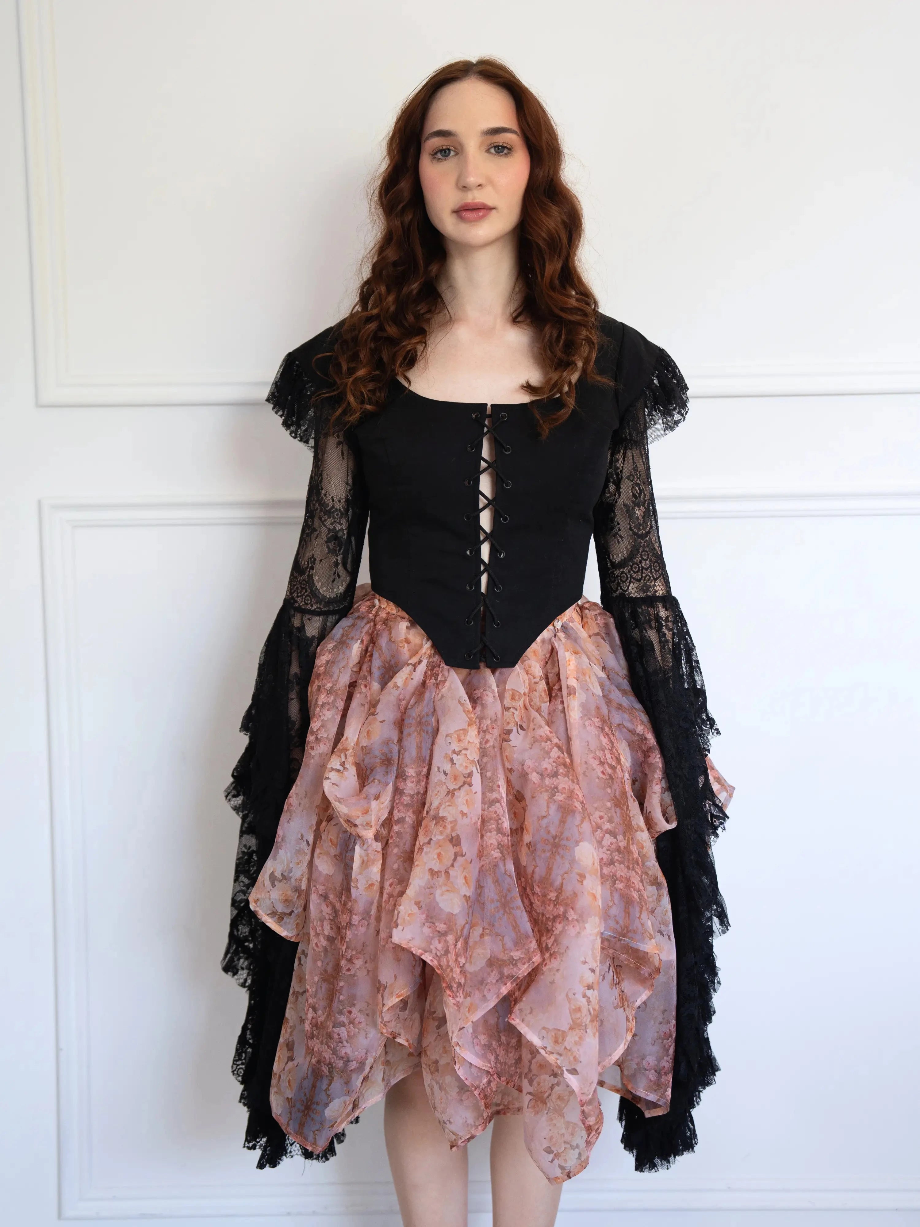 Model wearing The Twilight Bloom Bustle Skirt with a black lace-up corset top, showcasing the layered floral organza design.