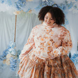 The Twilight Bloom Sleeper Hoodie paired with a floral skirt, modeled in a pastel floral backdrop. Oversized fit ideal for comfort and charm.