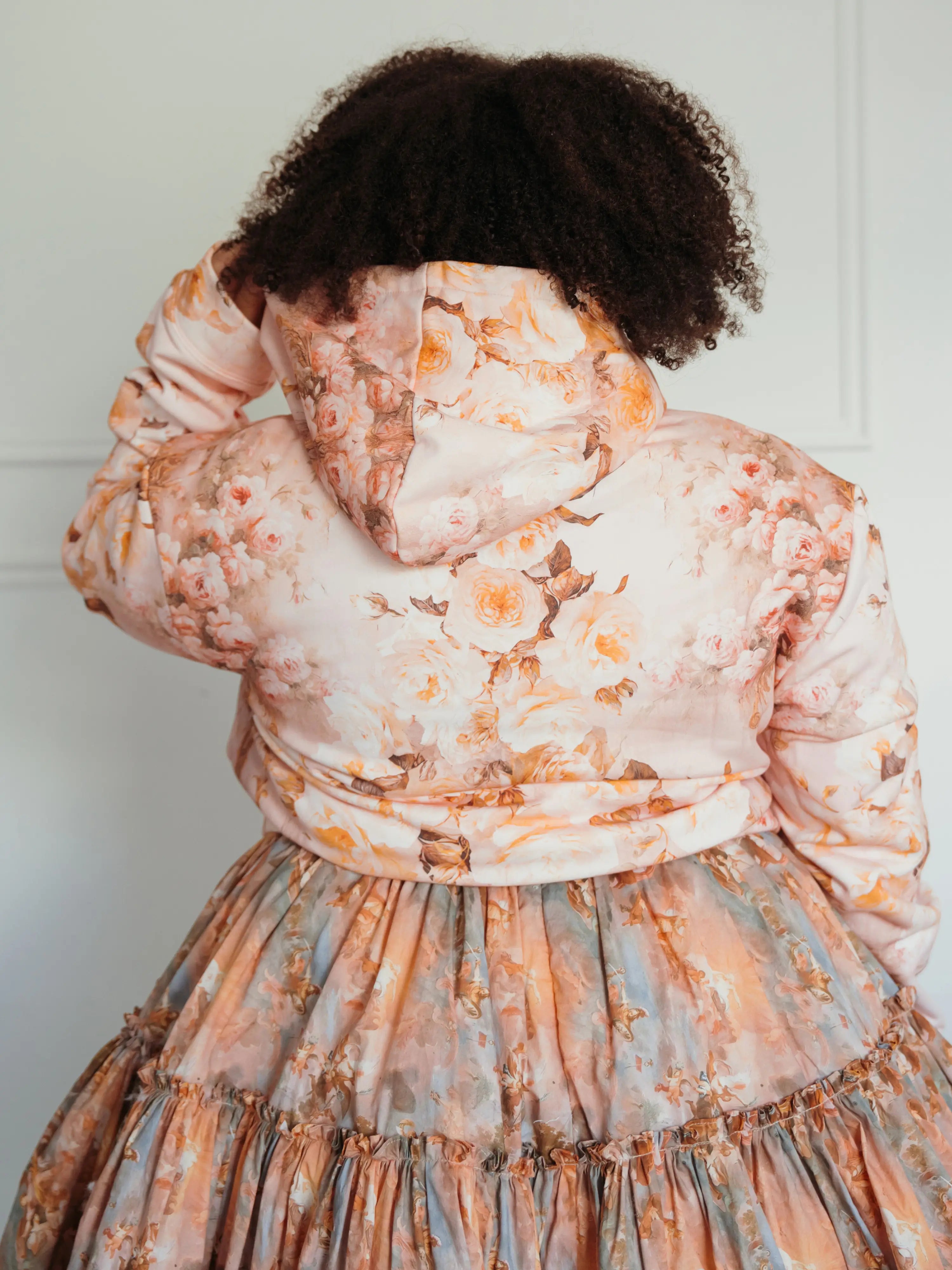 Back view of The Twilight Bloom Sleeper Hoodie showcasing detailed floral print and hood. Styled with a matching floral skirt for a romantic look.