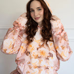 The Twilight Bloom Sleeper Hoodie featuring pastel rose patterns, worn with a ruffled skirt. Ideal for cozy, whimsical fashion in hoodie tops.