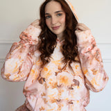 The Twilight Bloom Sleeper Hoodie featuring pastel rose patterns, worn with a ruffled skirt. Ideal for cozy, whimsical fashion in hoodie tops.