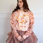 The Twilight Bloom Sleeper Hoodie styled with a layered floral skirt. Features soft pink tones and vintage rose design for cozy, feminine fashion.