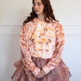 The Twilight Bloom Sleeper Hoodie styled with a layered floral skirt. Features soft pink tones and vintage rose design for cozy, feminine fashion.