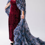 Scarlet red velvet midi dress paired with a flowing blue and pink floral print cape.