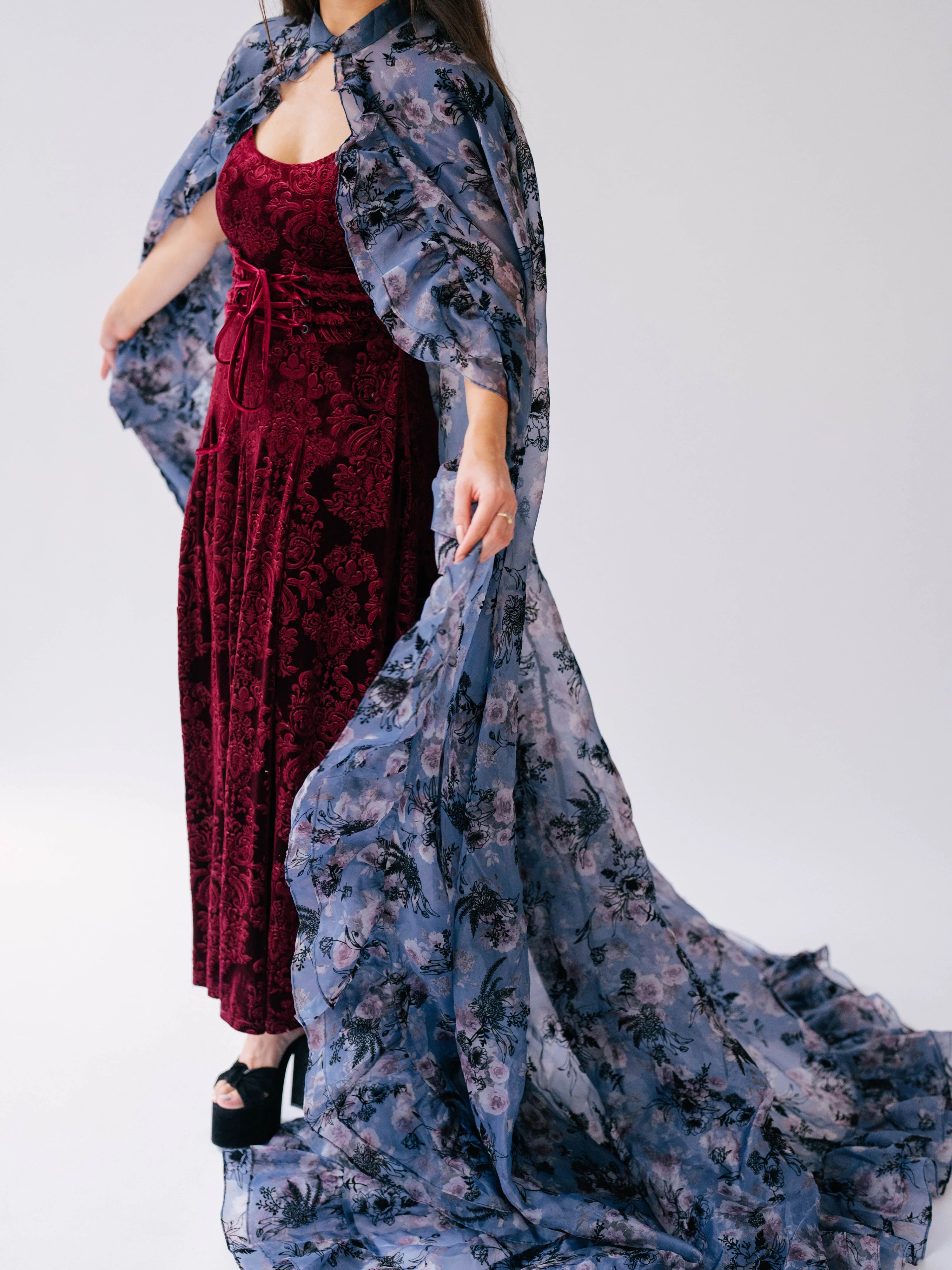 Scarlet red velvet midi dress paired with a flowing blue and pink floral print cape.