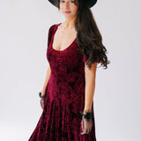 A scarlet red velvet victorian dress with a fitted bodice, floral pattern and flowing skirt.