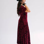 A scarlet red velvet midi dress side view with black lace floral applique evening gloves.