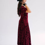 A scarlet red velvet midi dress side view with black lace floral applique evening gloves.