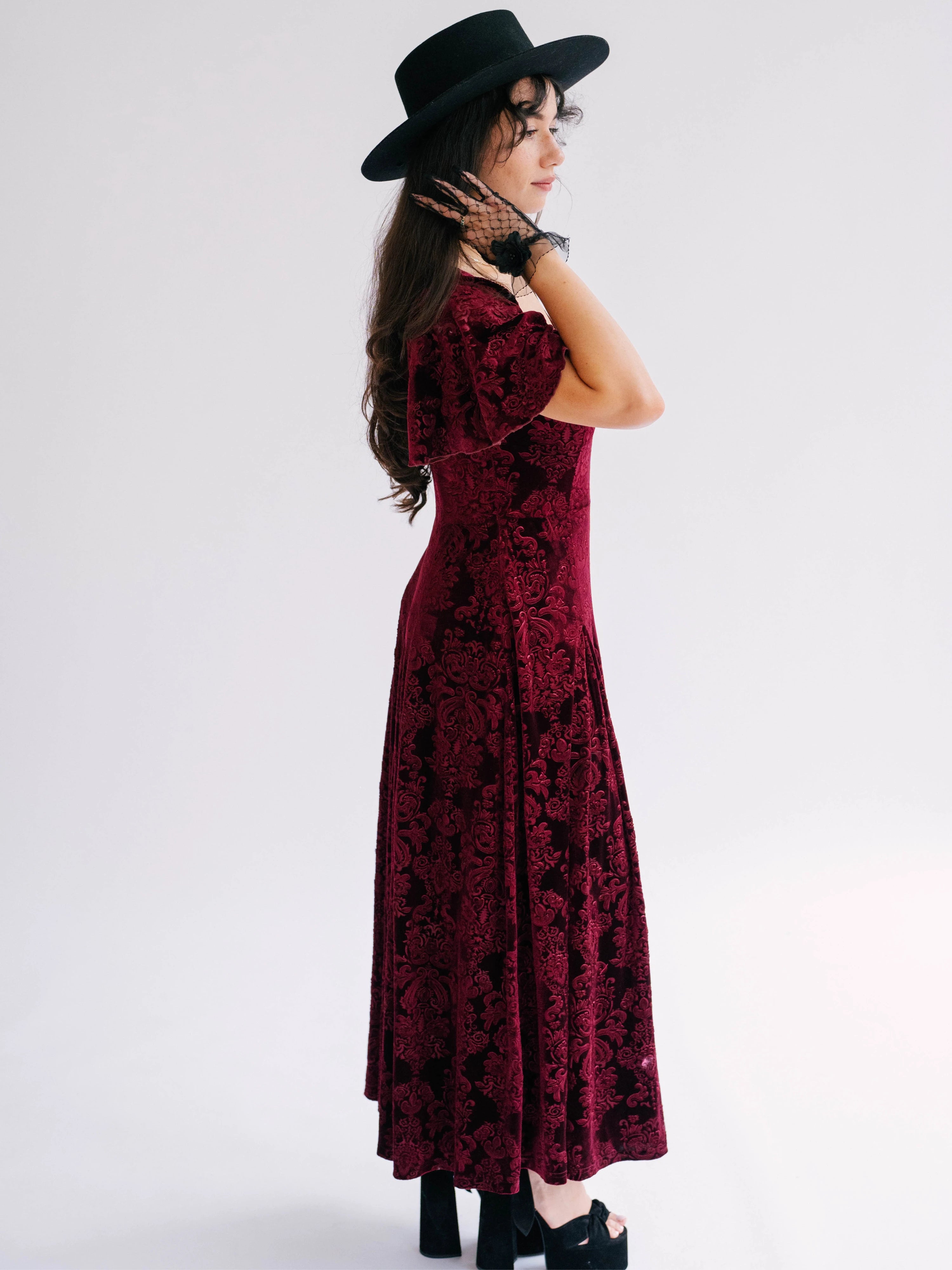 A scarlet red velvet midi dress side view with black lace floral applique evening gloves.