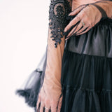 Intricate black beaded lace design opera glove adorning a forearm.