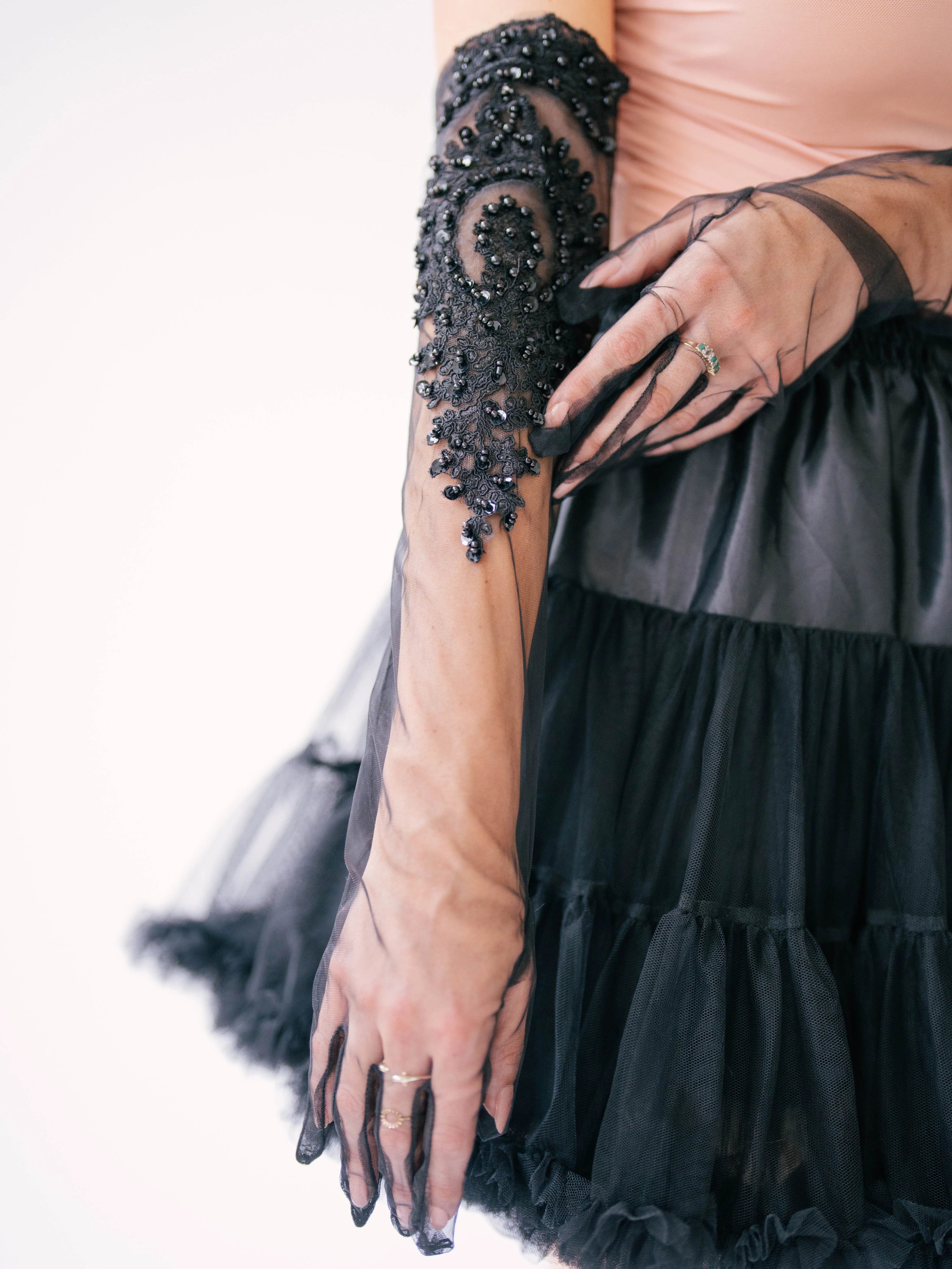 Intricate black beaded lace design opera glove adorning a forearm.