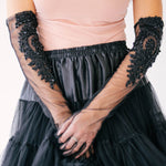 Elegant black tulle mini skirt paired with sheer lace evening gloves and a blush pink blouse.