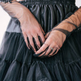The Viola Adorned Lace Gloves resting against a black tulle mini skirt.
