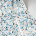 The oversized bow, zoomed in shows a floral fabric with blue and pink watercolor-style flowers on a white background. This print is called Wildbloom. 