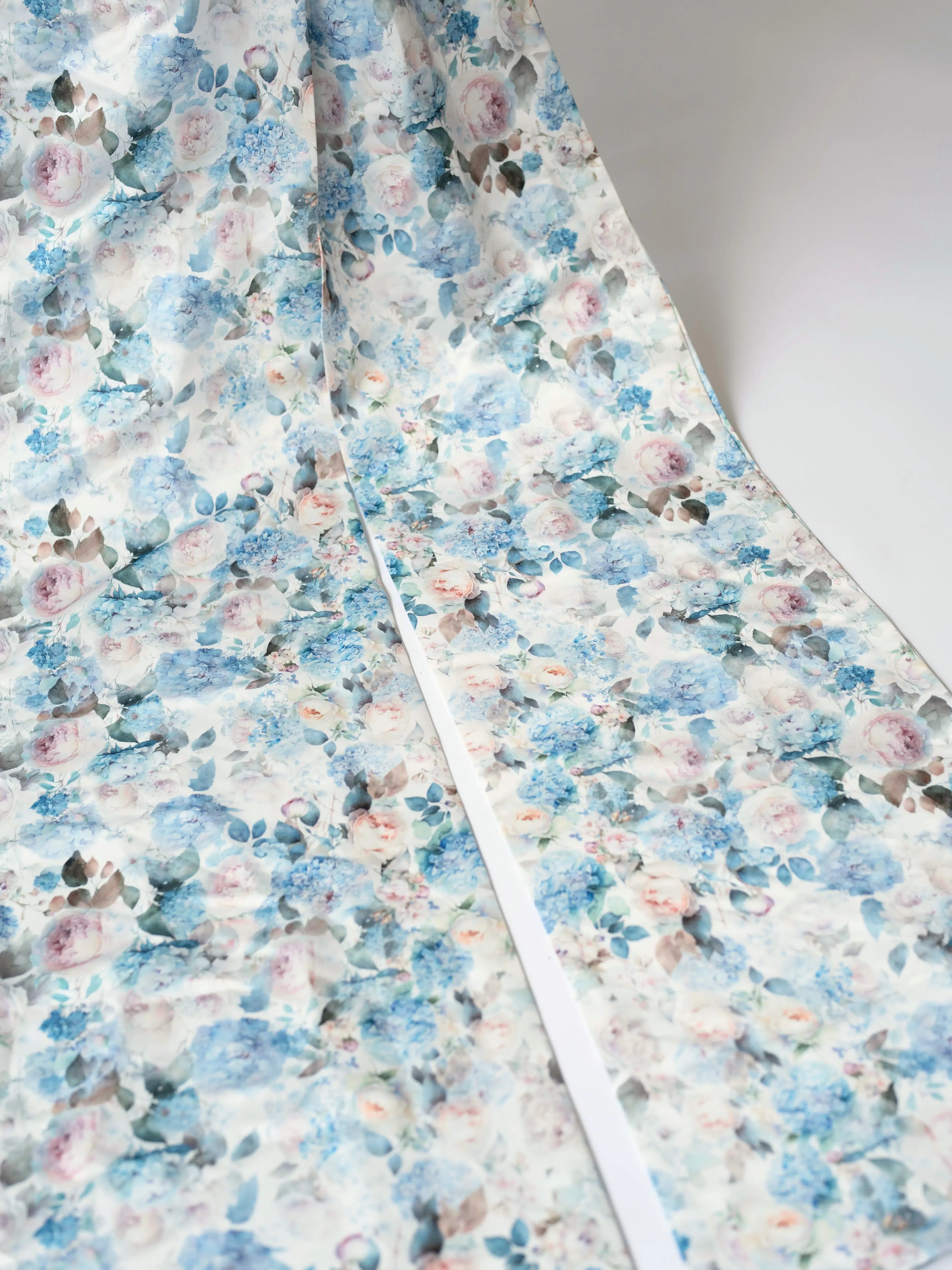 The oversized bow, zoomed in shows a floral fabric with blue and pink watercolor-style flowers on a white background. This print is called Wildbloom. 