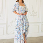 The Wildbloom Josephine Ball Gown has puff sleeves and a ruffled asymmetric hem in light blue and white.