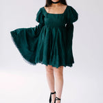 Emerald green puff-sleeve mini dress with a full skirt and black platform sandals.