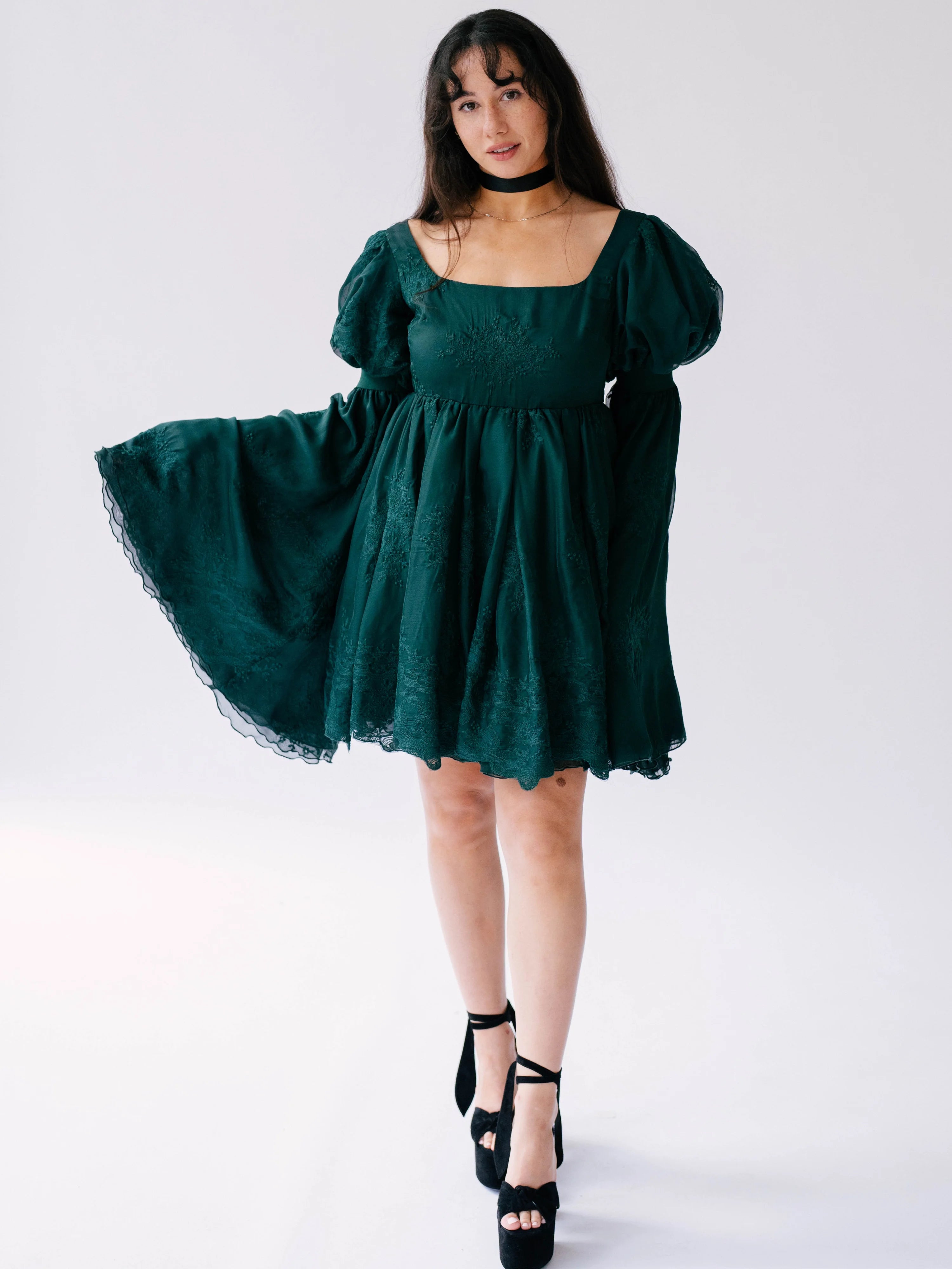 Emerald green puff-sleeve mini dress with a full skirt and black platform sandals.