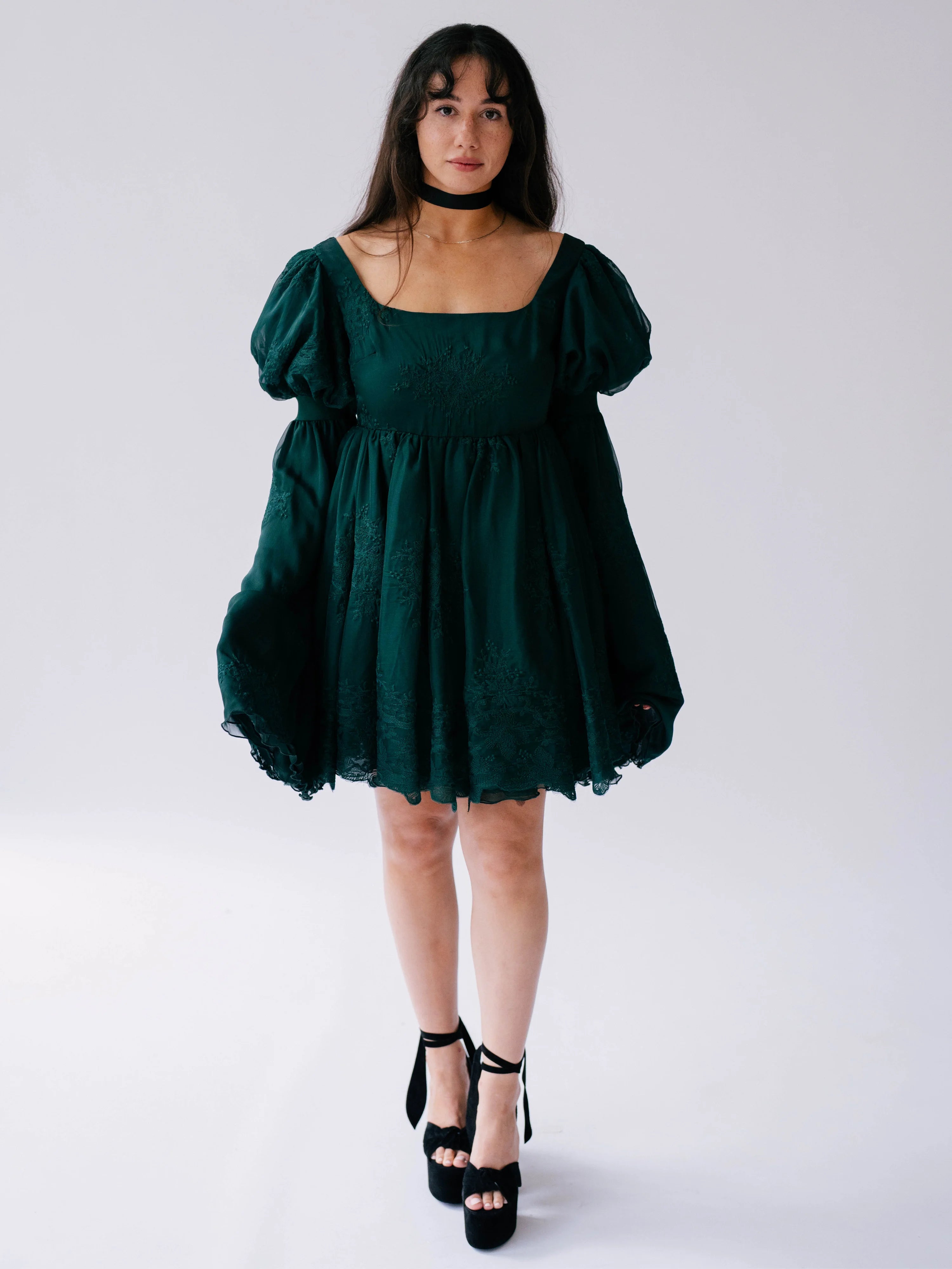 Dark emerald green mini dress with bell sleeves and a black choker necklace.