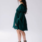 Dark emerald green mini dress with flowy long sleeves and a ruffled hem.