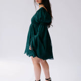 Dark emerald green mini dress with flowy long sleeves and a ruffled hem.