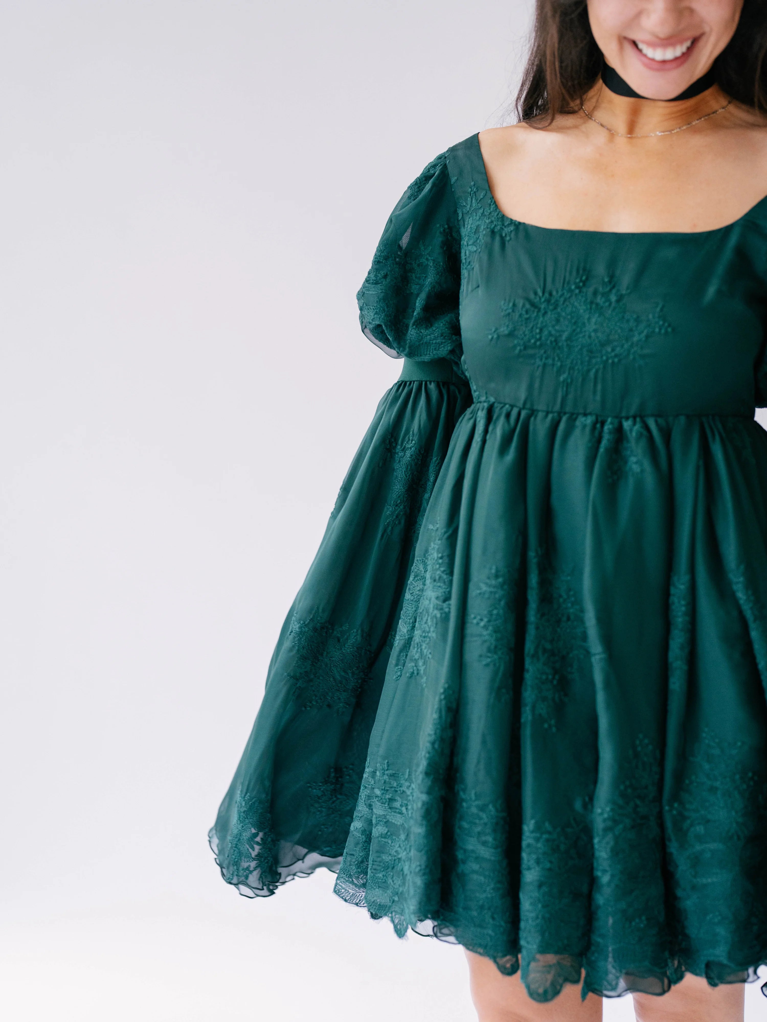 Emerald green holiday mini dress with puffy bell sleeves and embroidered details.