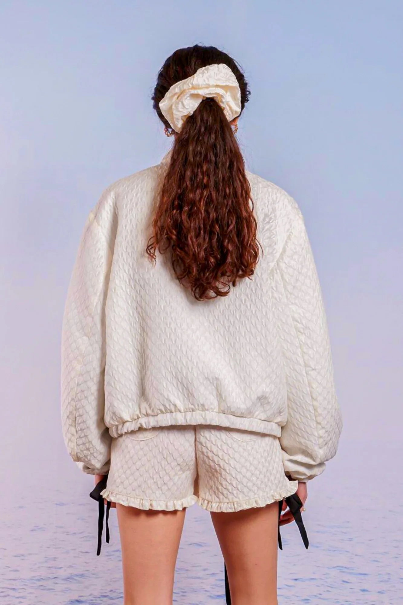 Person with long brown hair in a white sweater and shorts showcases Adella Jacquard Bomber