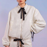 White textured romper with puffy sleeves and black bow details styled with Adella Jacquard Bomber