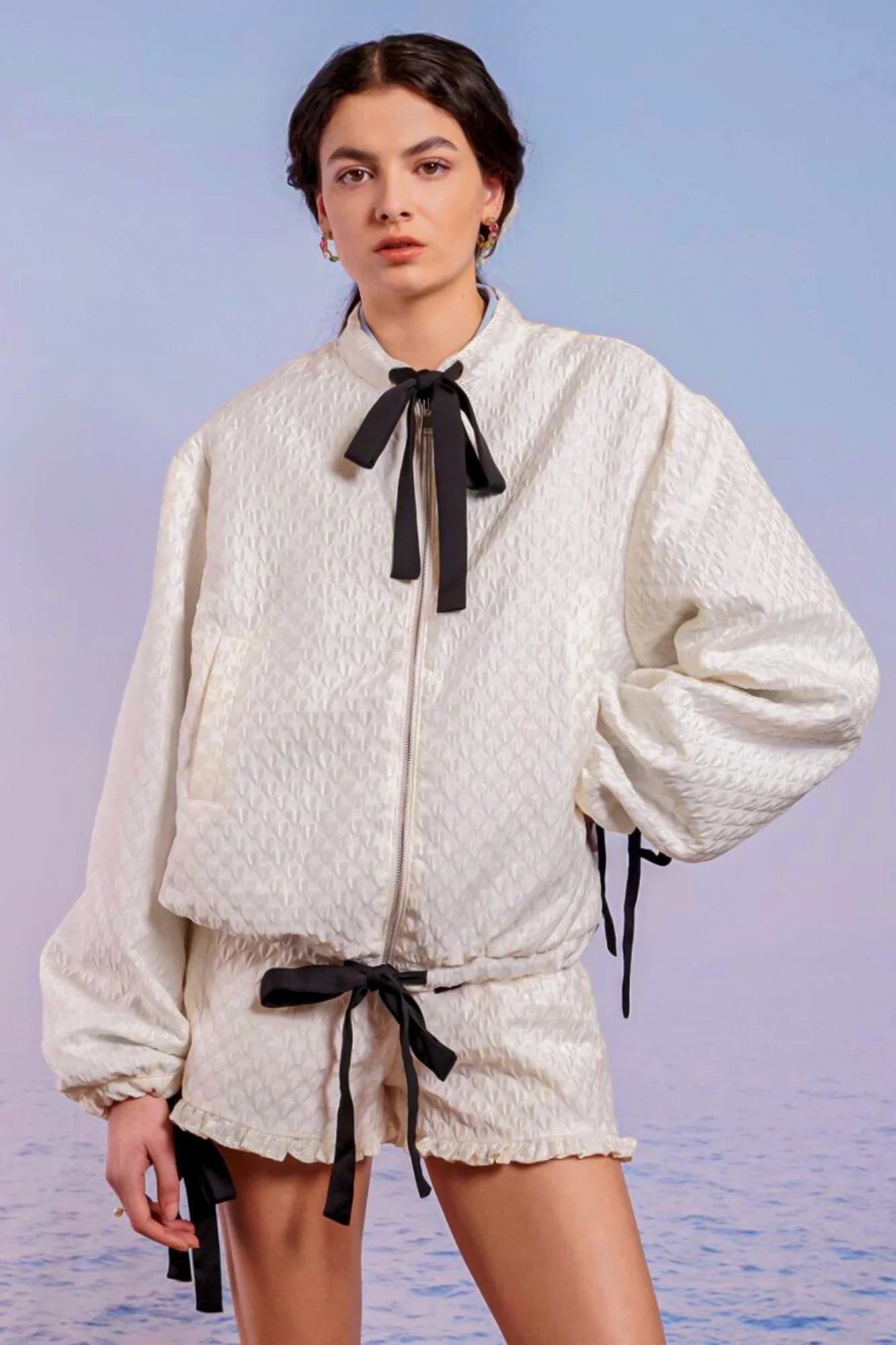 White textured romper with puffy sleeves and black bow details styled with Adella Jacquard Bomber