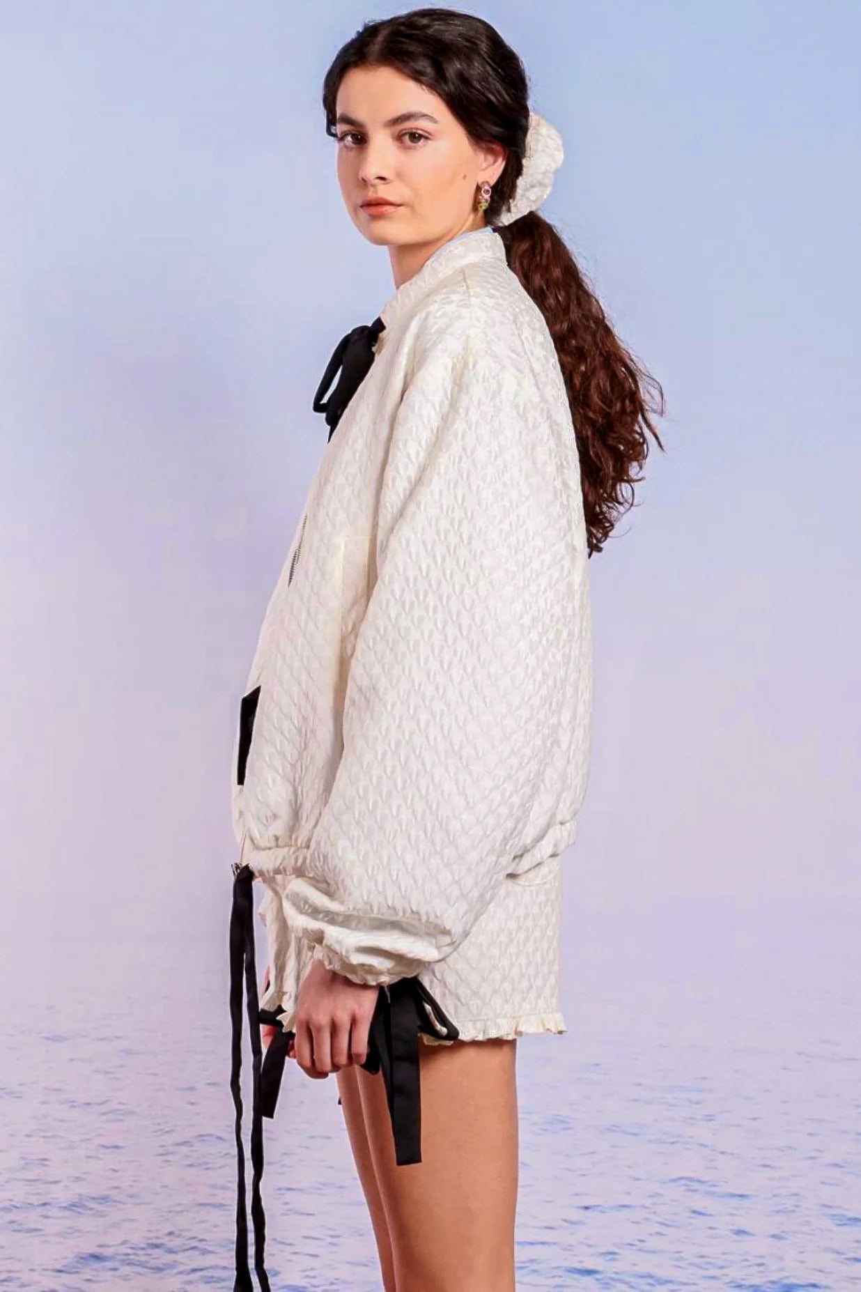 Woman in white oversized cardigan with black bows, featuring Adella Jacquard Bomber details