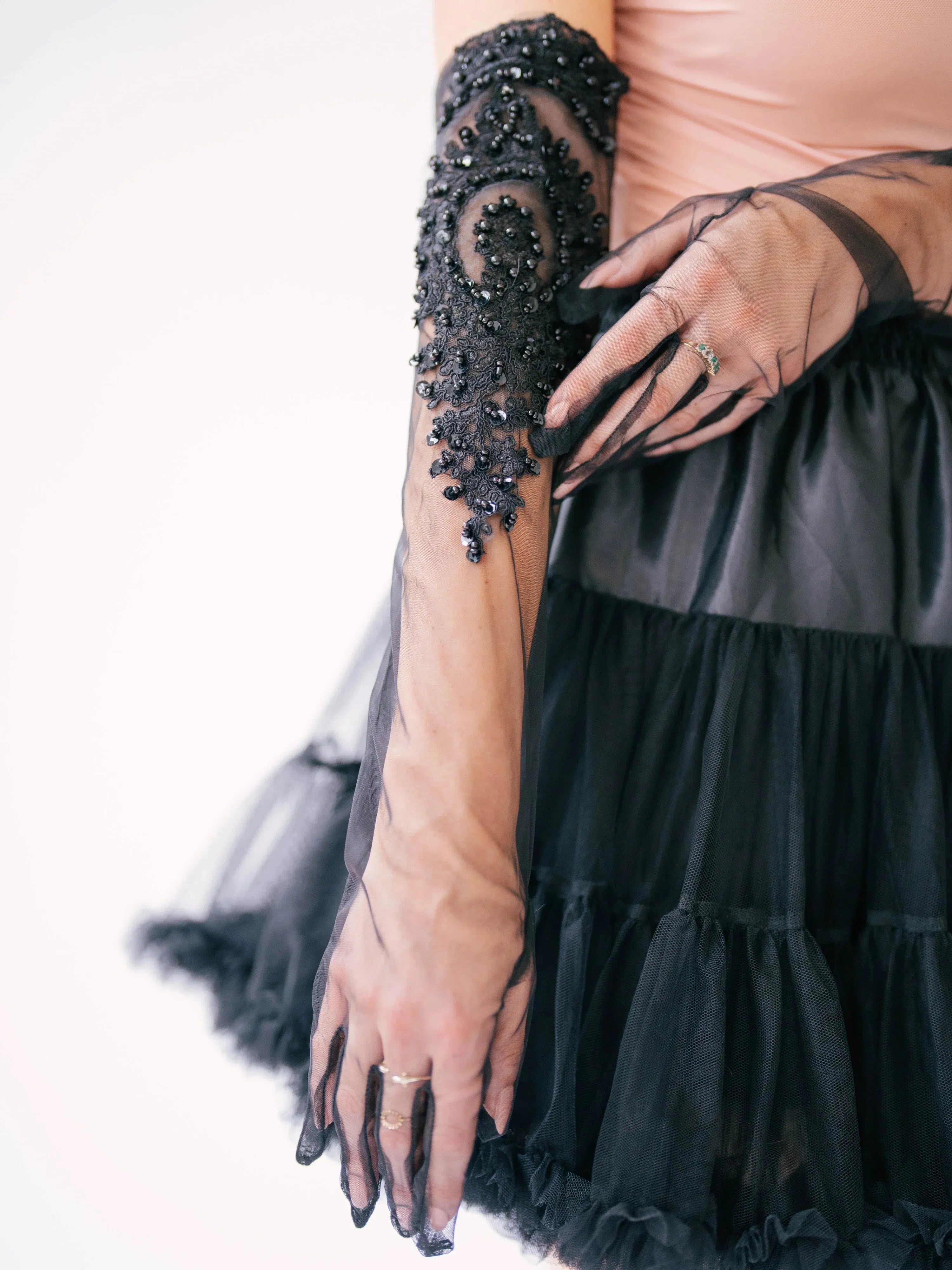 Intricate black beaded lace design evening gloves adorning a forearm.