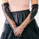Elegant black tulle mini skirt paired with sheer lace formal evening gloves and a blush pink blouse.