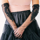 Elegant black tulle mini skirt paired with sheer lace formal evening gloves and a blush pink blouse.