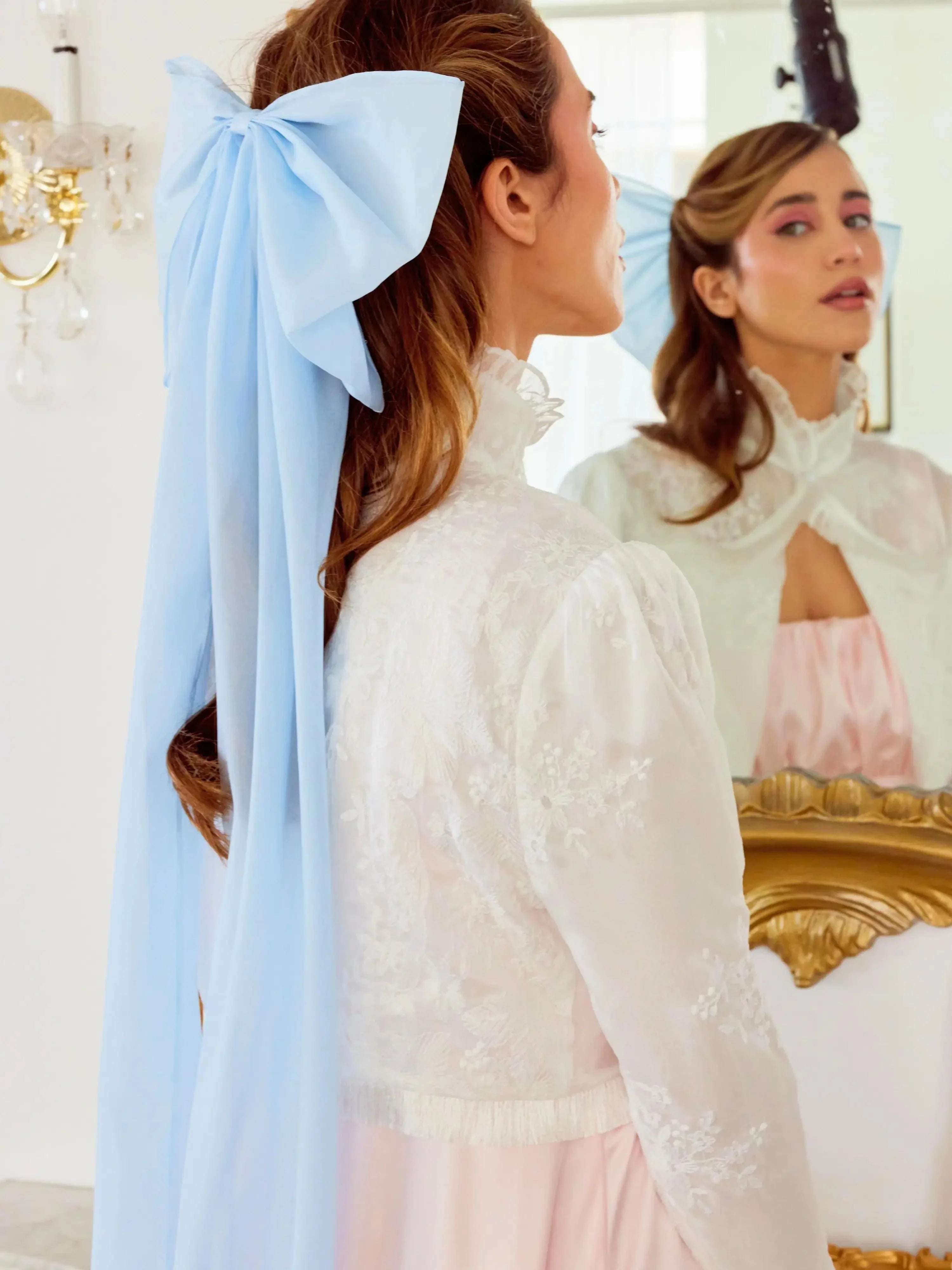 Woman in a white top showcasing The Alice Blue Giant Flutter Bow hairstyle accessory