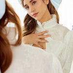 Caylee wearing the Alice Blue Grand Hair Bow styled with romantic waves and delicate lace attire, reflecting in a vintage mirror for a whimsical touch.