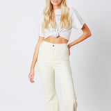 Young woman in cropped white top and cream flared Almost Famous Bell Bottom Jeans