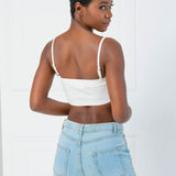 Woman in a white Atwood Camisole and light blue jeans, stylishly viewed from behind